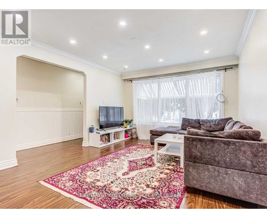A living room with a grey couch and a red rug.