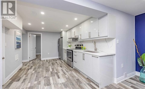 A kitchen with white cabinets and a wooden floor.