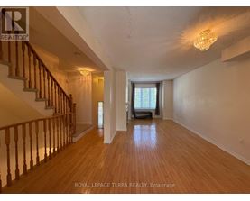 A spacious room with wooden floors and a staircase with wooden railings.