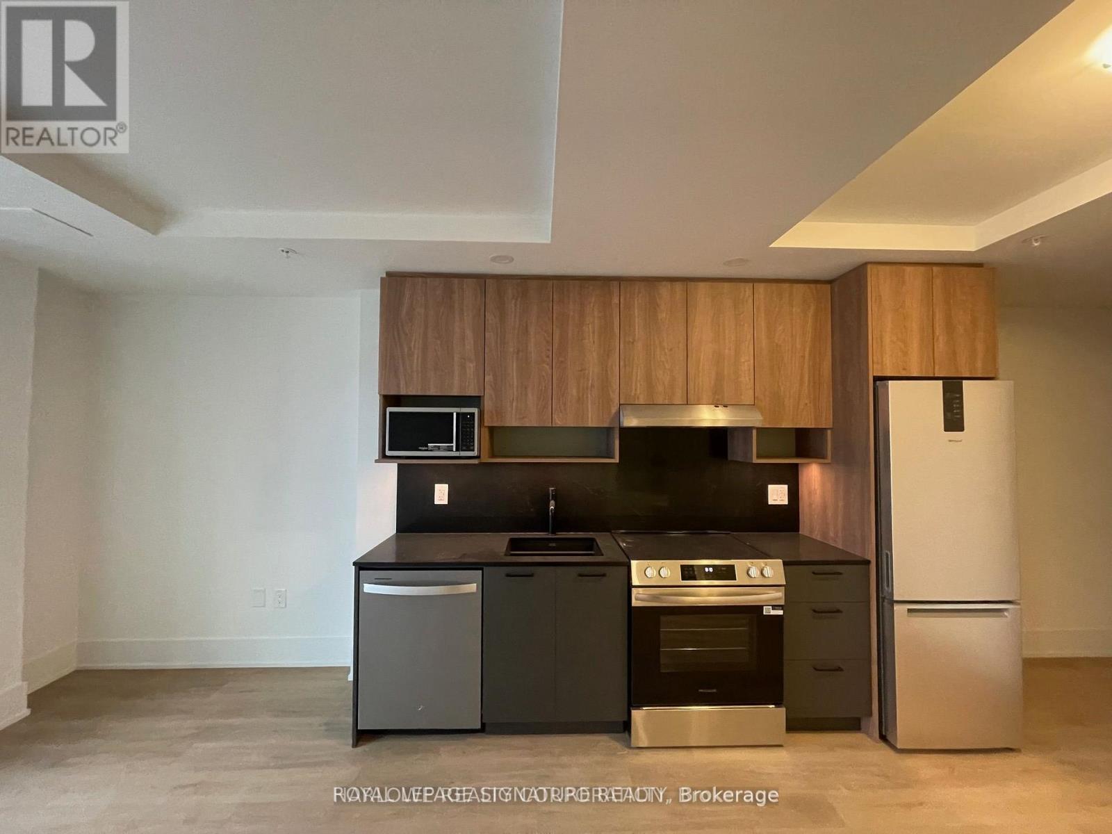 A modern kitchen with a black countertop and stainless steel appliances.
