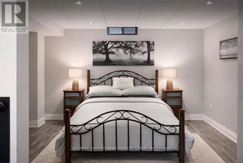 A bedroom with a large bed and a painting of a tree on the wall.