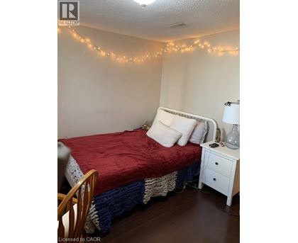 A bedroom with a bed, nightstand, and lights on the wall.