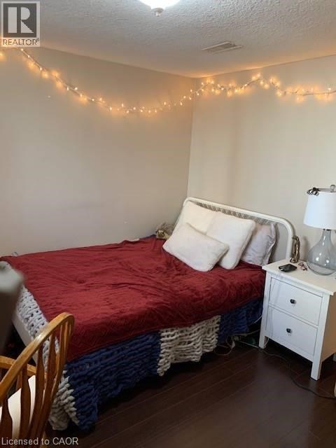 A bedroom with a bed, nightstand, and lights on the wall.