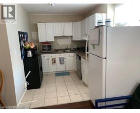 A kitchen with white cabinets and a black fridge.