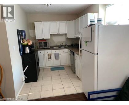 A kitchen with white cabinets and a black fridge.