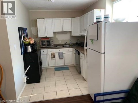 A kitchen with white cabinets and a black fridge.