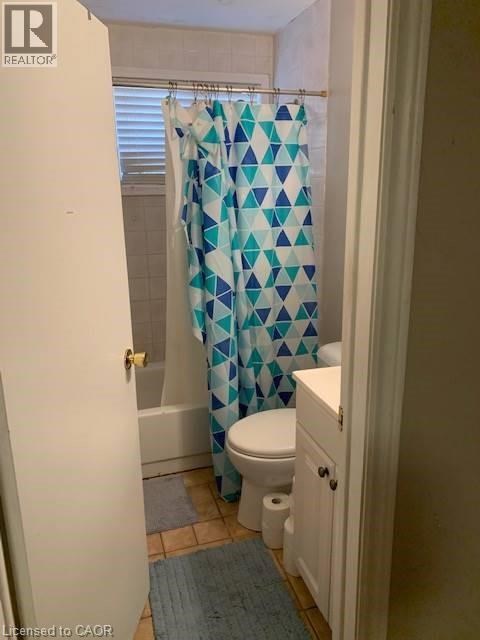 A bathroom with a toilet, a shower curtain and a rug.