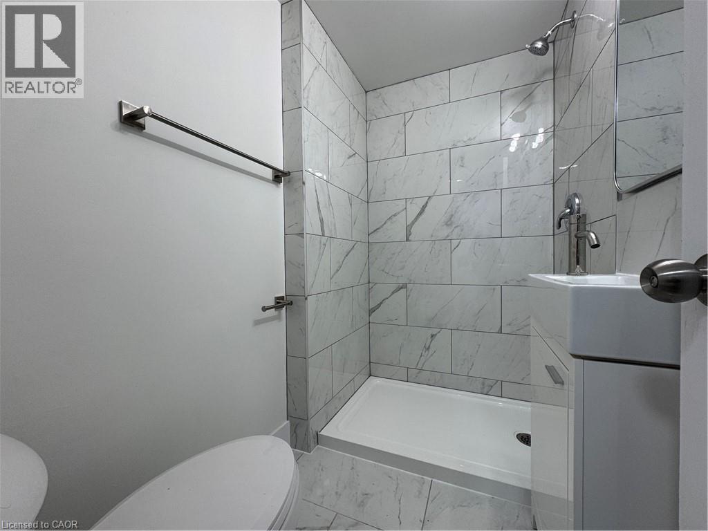 A white toilet sits next to a walk-in shower with a marble tile wall.
