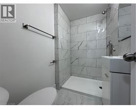 A white toilet sits next to a walk-in shower with a marble tile wall.