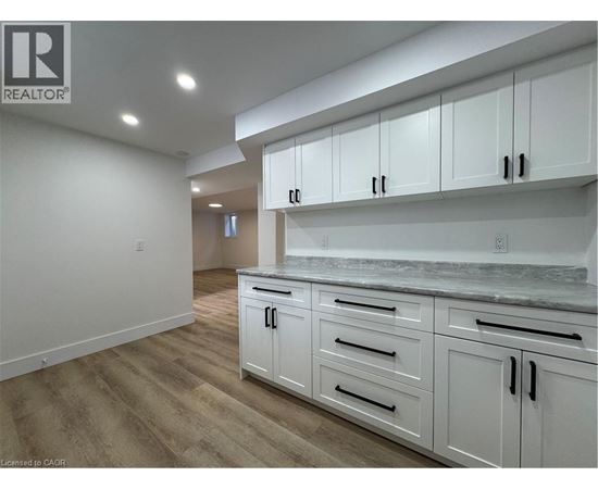 A kitchen with white cabinets and a marble countertop.