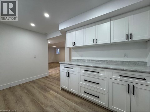 A kitchen with white cabinets and a marble countertop.