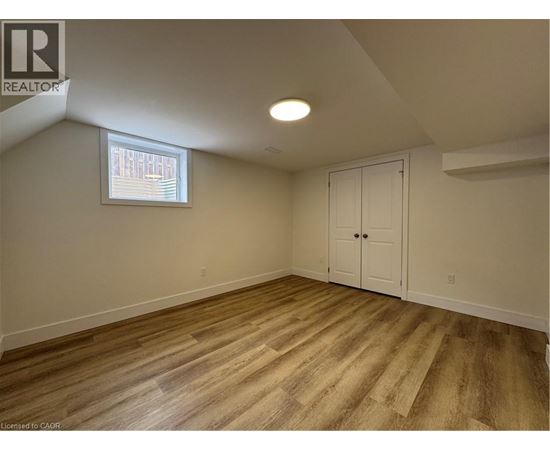 A room with wooden flooring and a window with blinds.