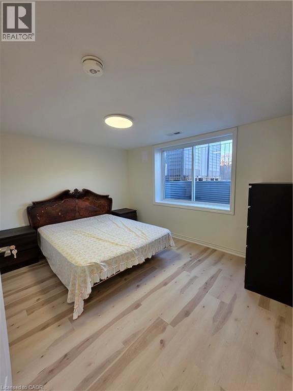 A bedroom with a bed, wooden floor, and a window.