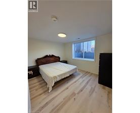 A bedroom with a bed, wooden floor, and a window.