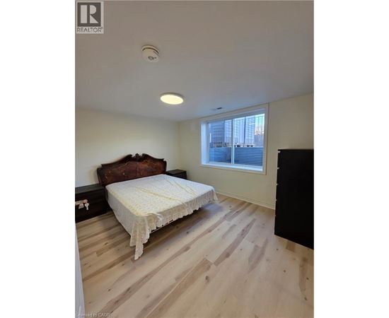 A bedroom with a bed, wooden floor, and a window.