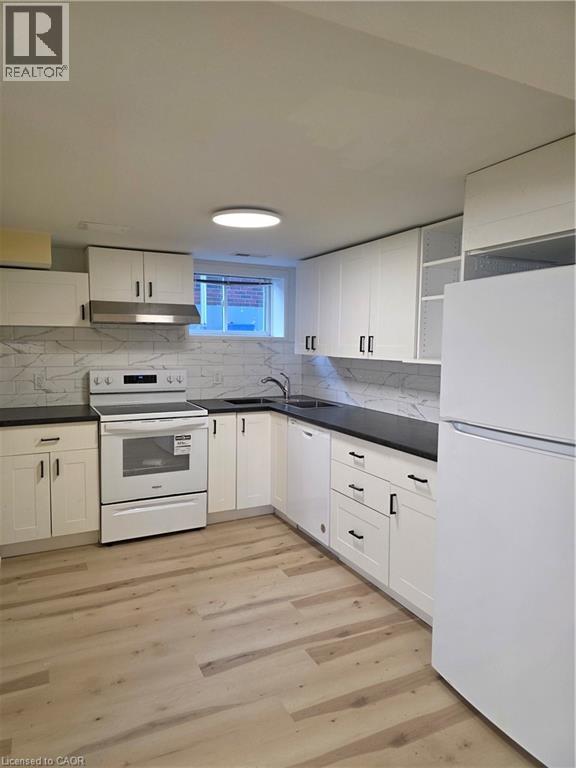 A kitchen with white appliances and wooden floors.