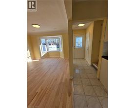 A room with wooden floors and a doorway leading to another room.