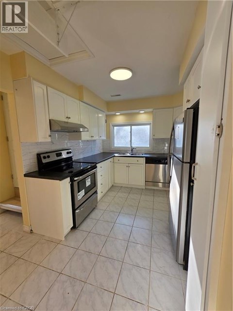 A kitchen with white cabinets and black appliances.