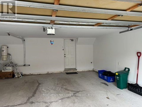 A garage with a white door and a red shovel on the right side.