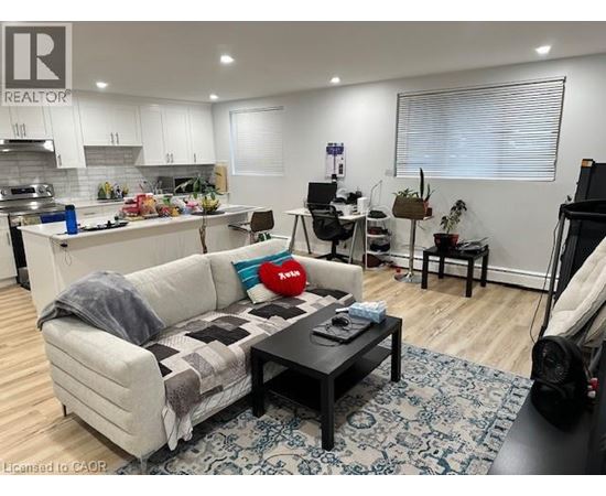 A living room with a couch, coffee table, and a kitchen area in the background.