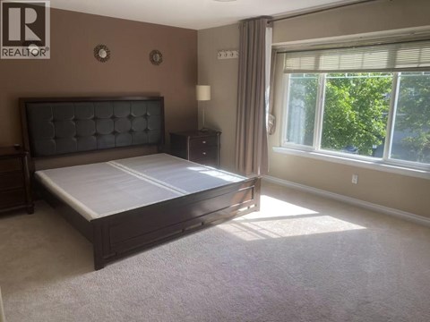 A bedroom with a large bed and a window letting in sunlight.