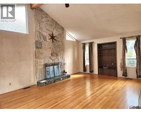 A living room with a stone fireplace and wood flooring.