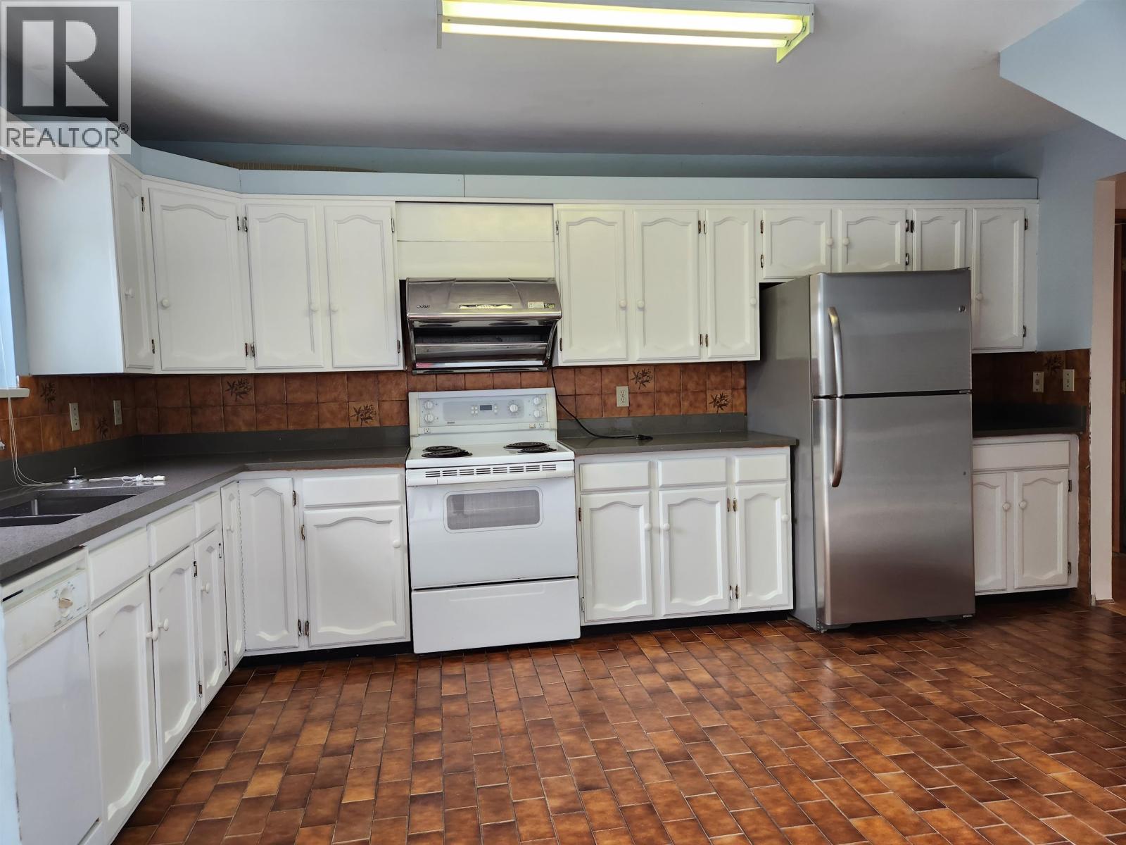 A kitchen with white cabinets and a tile floor.