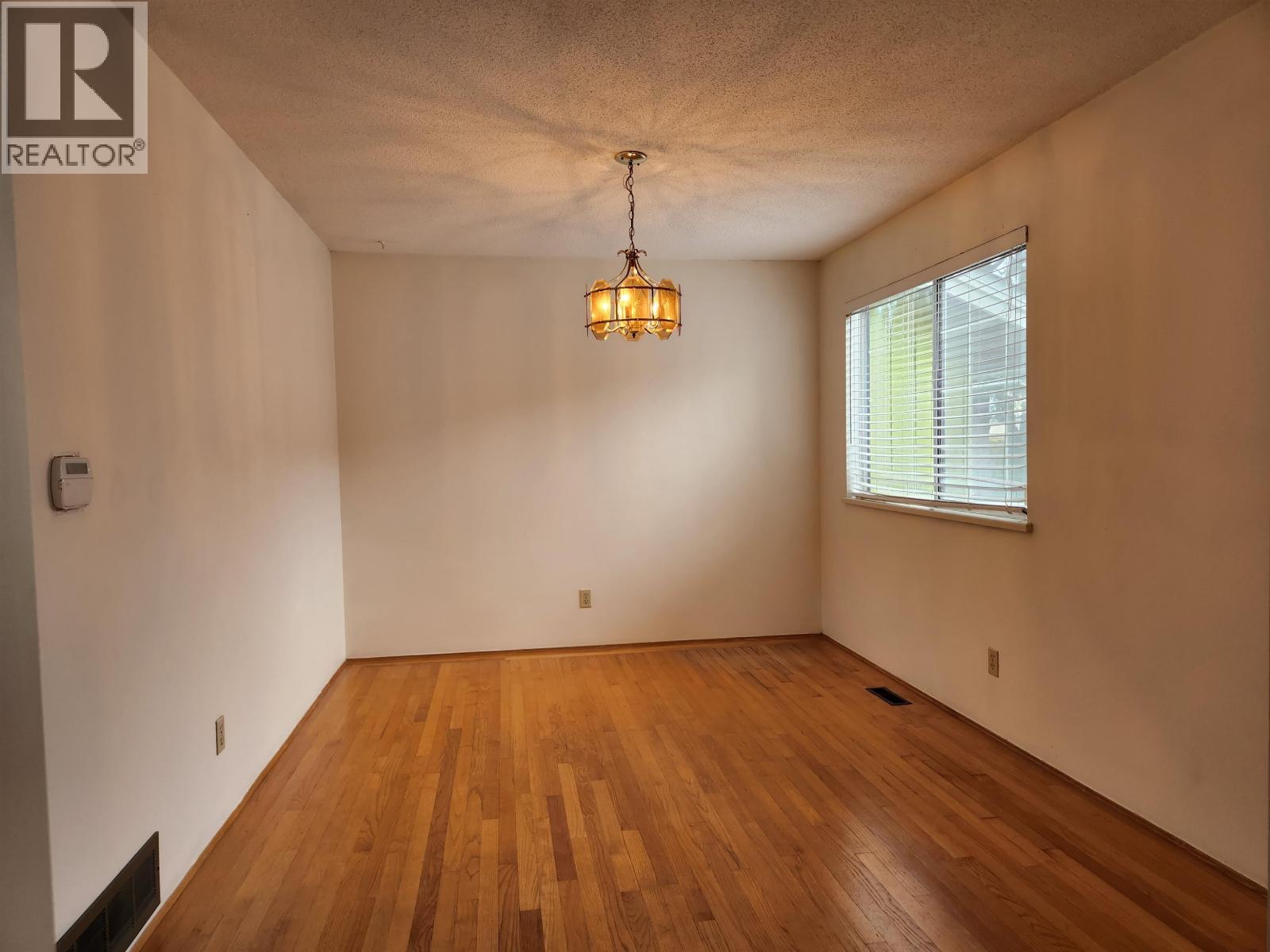 A room with wooden floors and a window with blinds.