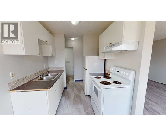 A white kitchen with a stove, sink, and cabinets.