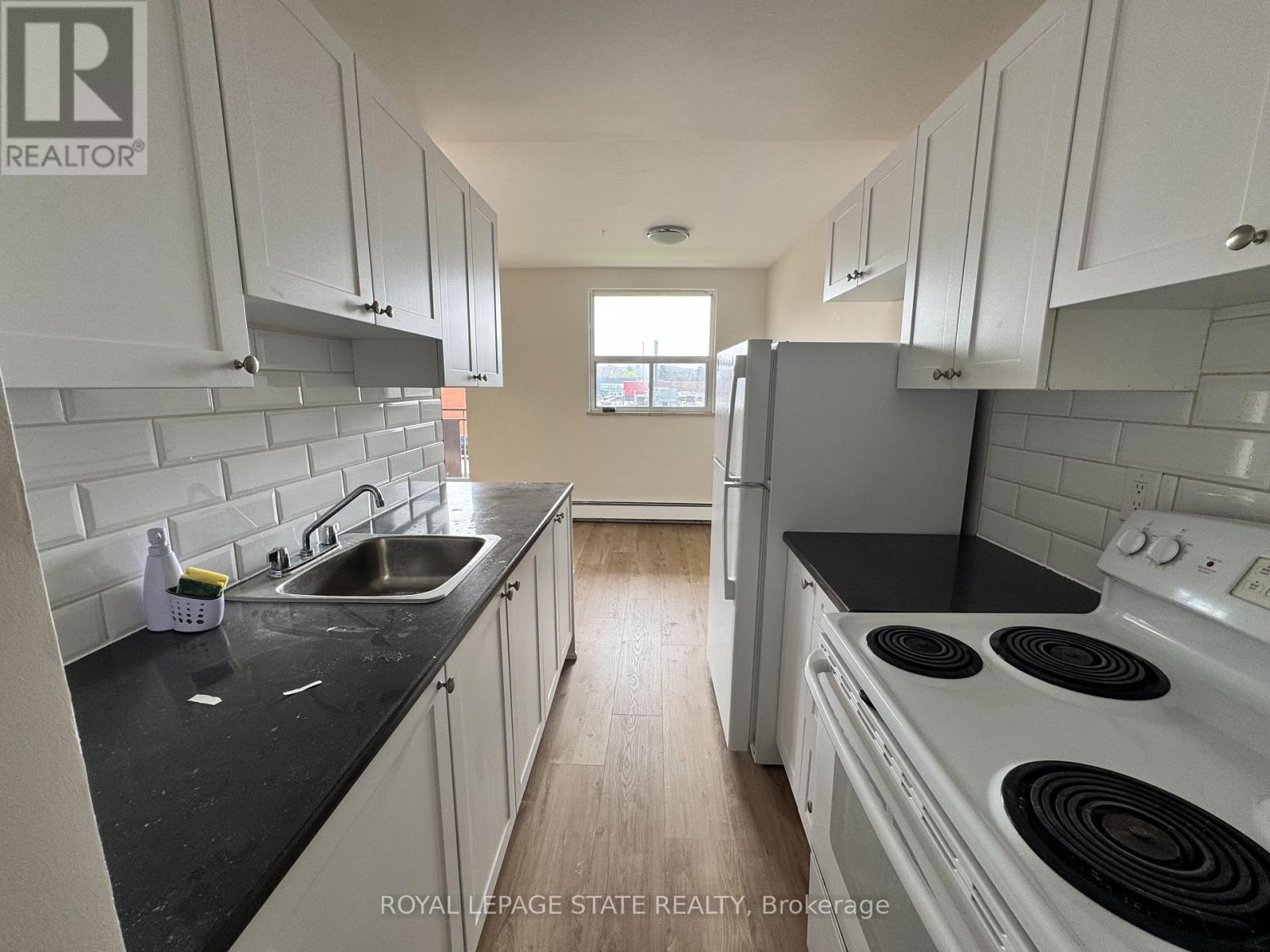 A kitchen with white cabinets and black countertops.