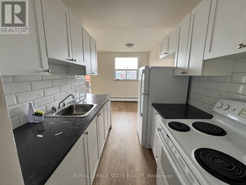 A kitchen with white cabinets and black countertops.