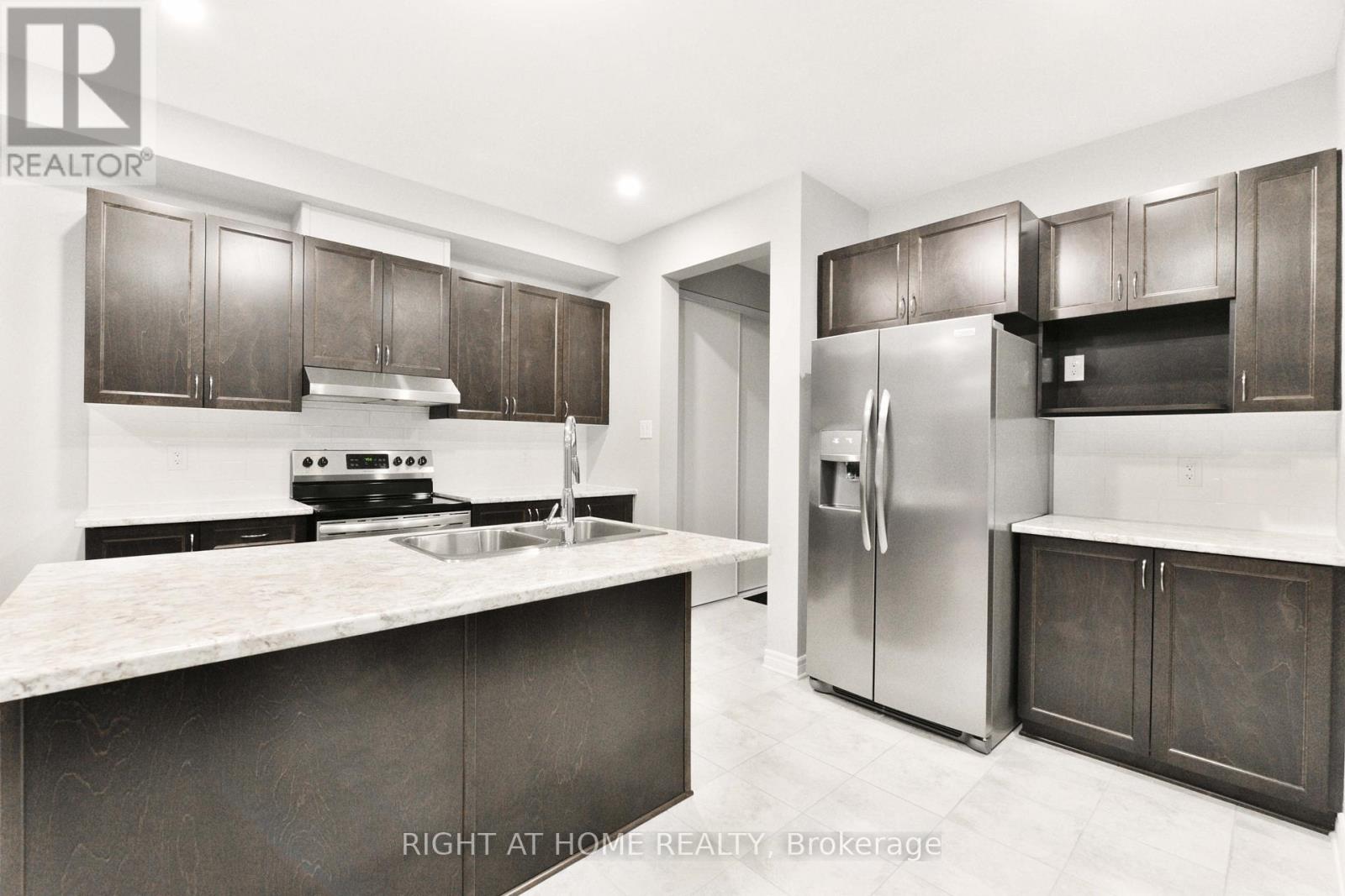 A modern kitchen with dark brown cabinets and a marble countertop.