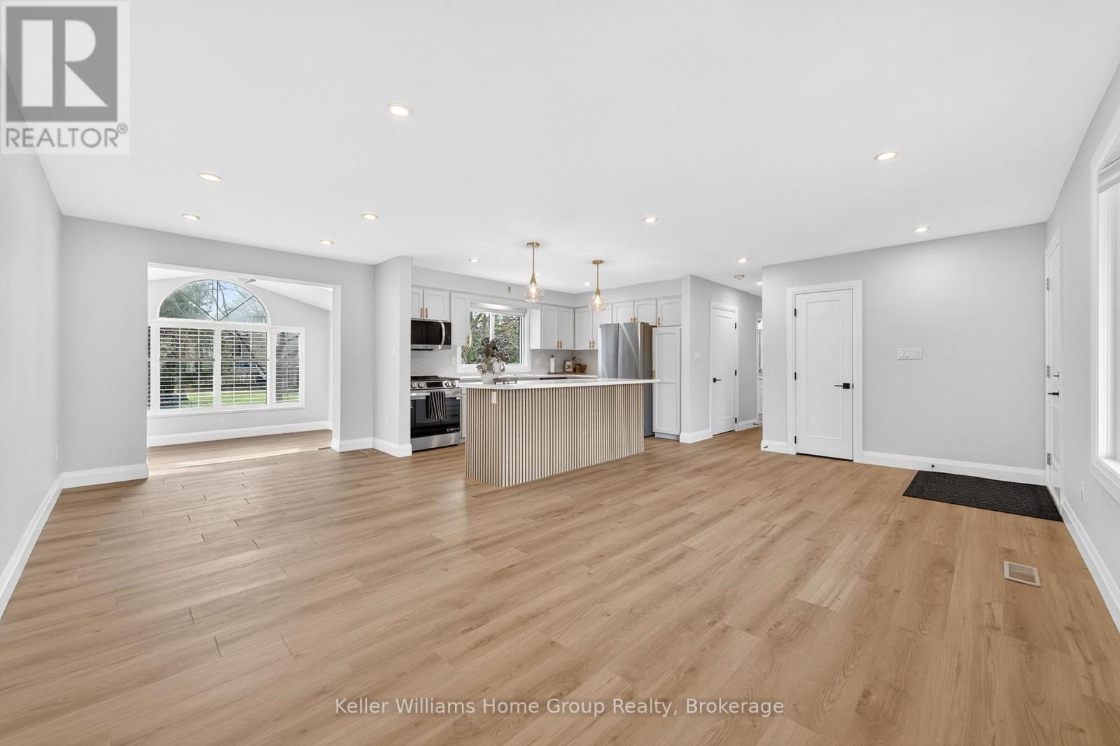A spacious living room with wooden flooring and white walls.