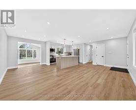 A spacious living room with wooden flooring and white walls.