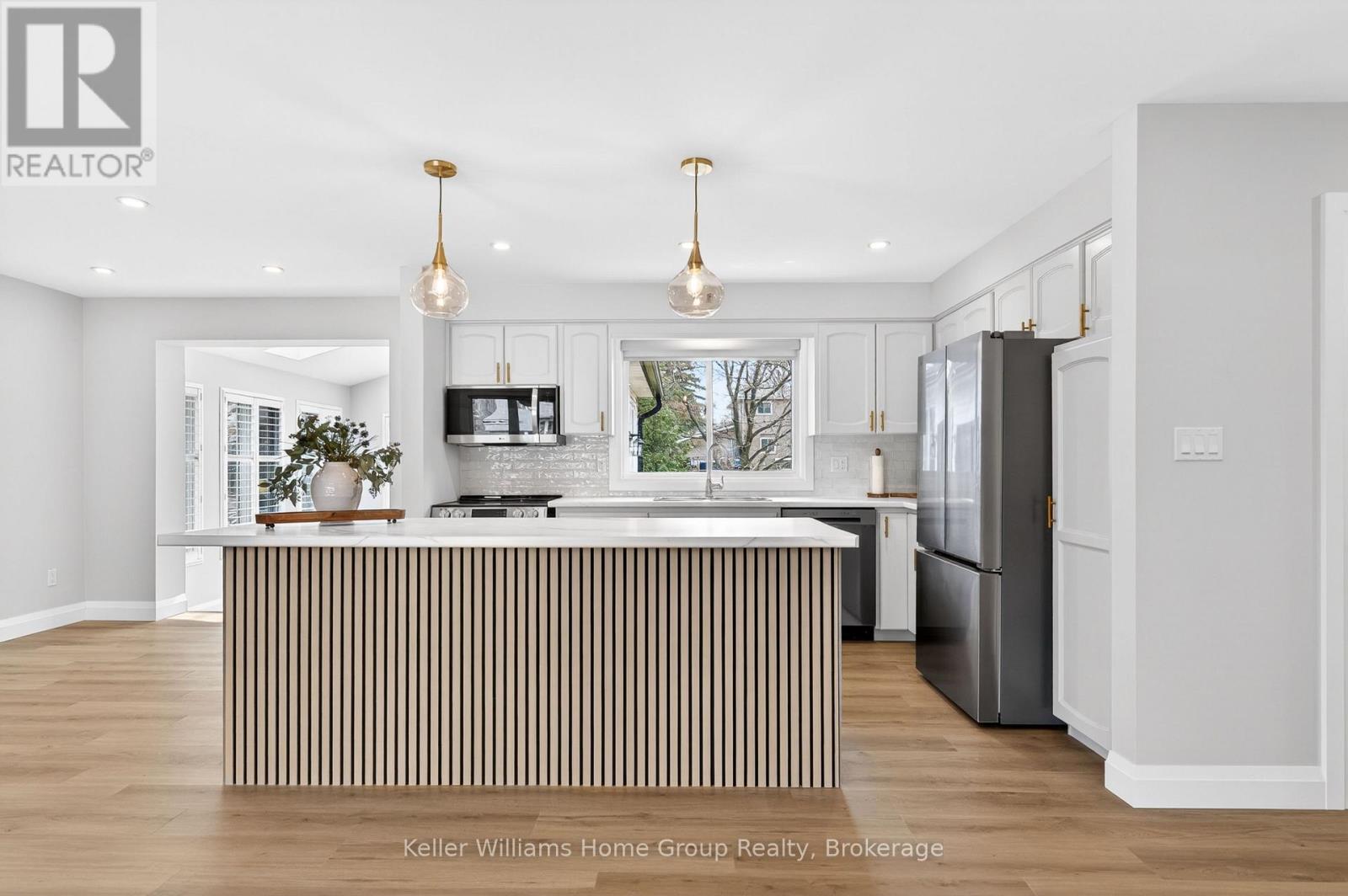 A modern kitchen with a central island and a refrigerator to the right.