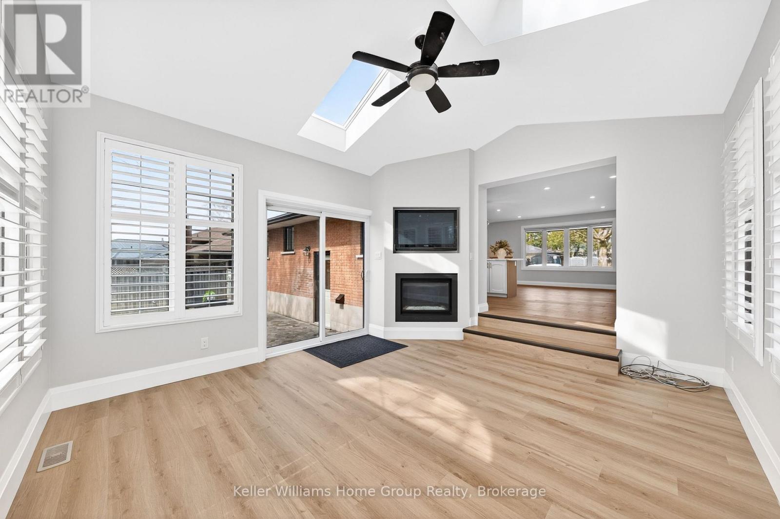A well-lit, spacious room with a ceiling fan and a television.