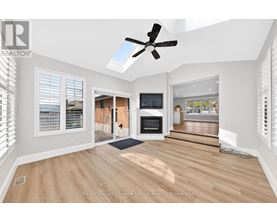 A well-lit, spacious room with a ceiling fan and a television.