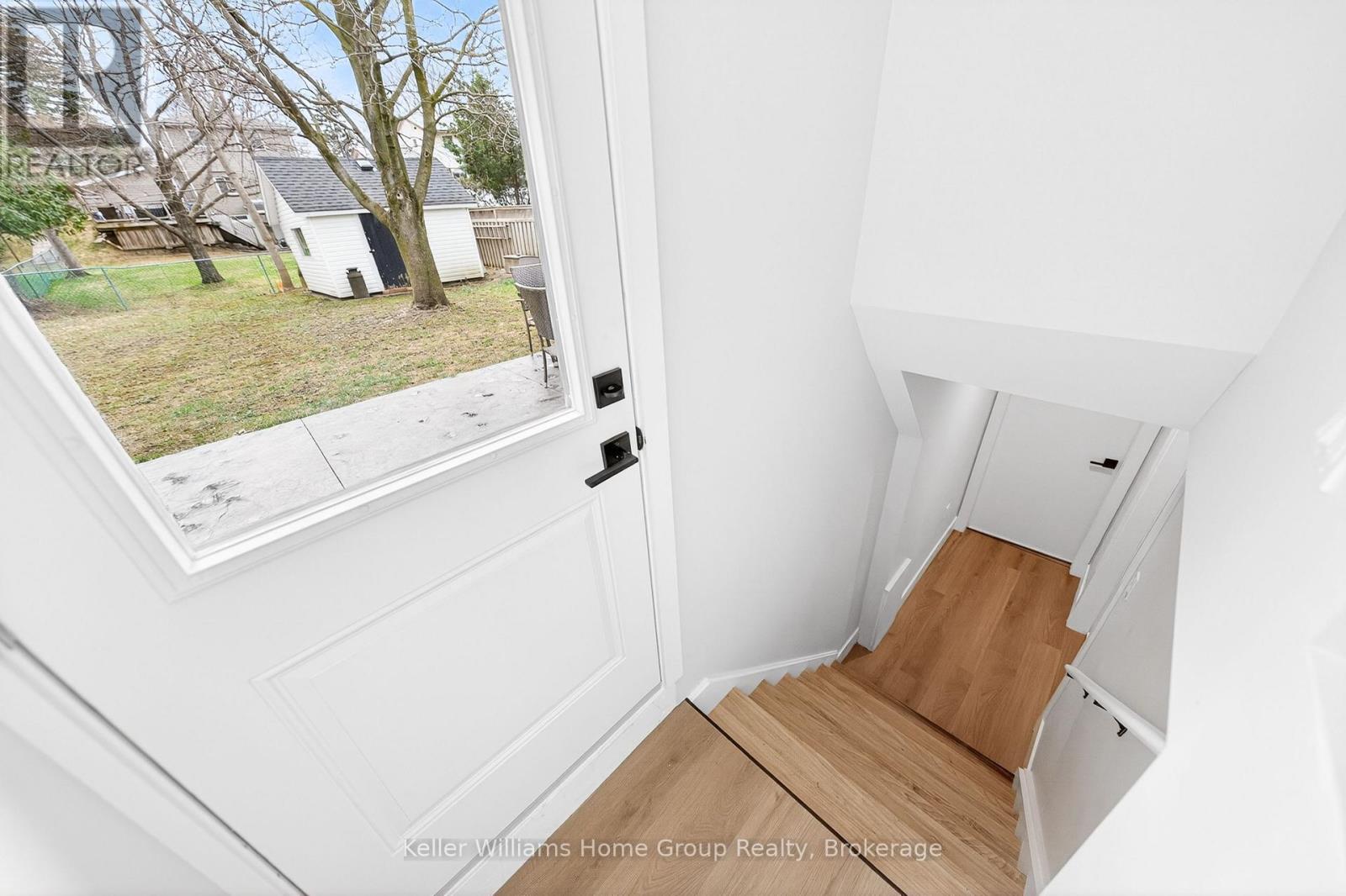 A white interior space with a wooden staircase leading to a second floor.