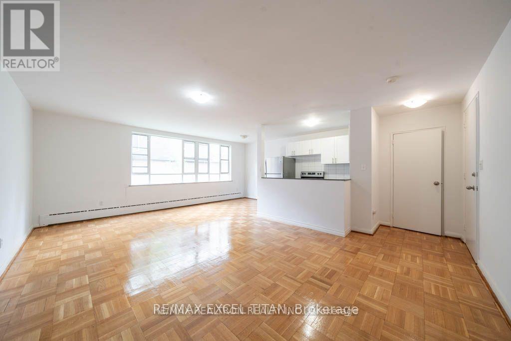 A spacious room with wooden flooring and white walls.