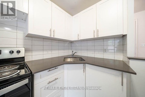 A kitchen with white cabinets and a stove top oven.