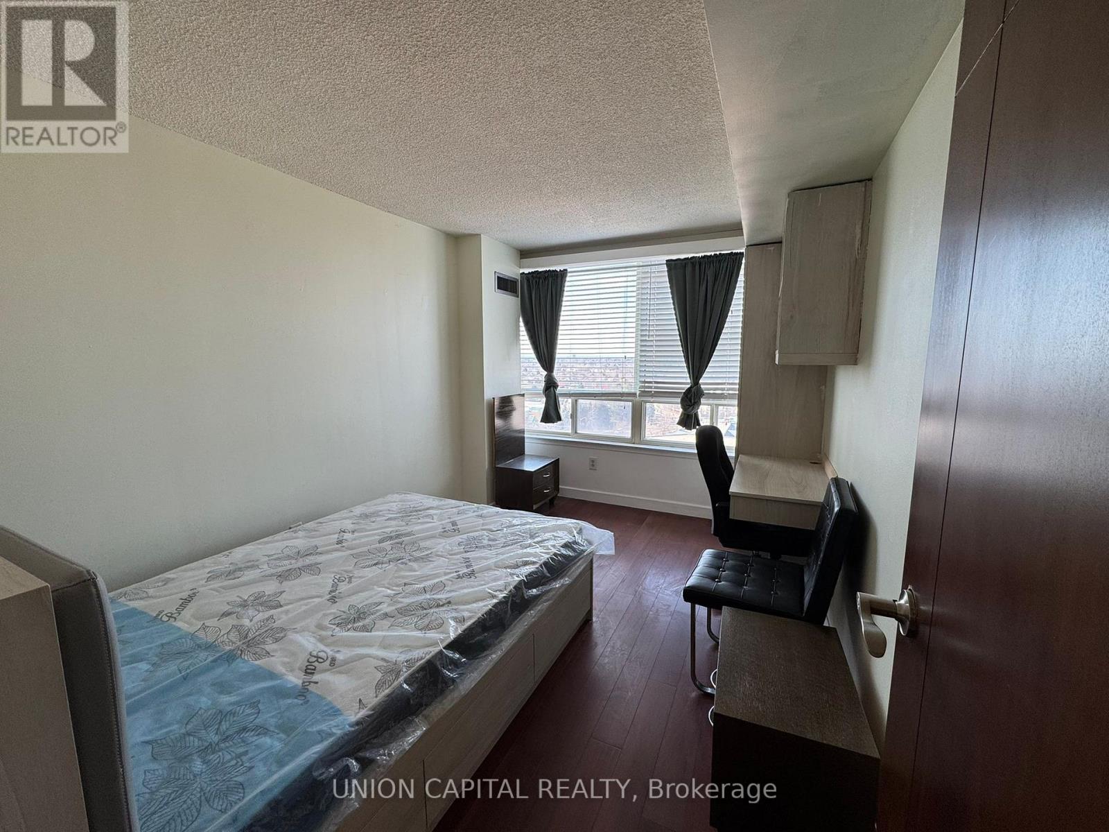 A bedroom with a bed, chair, and window.