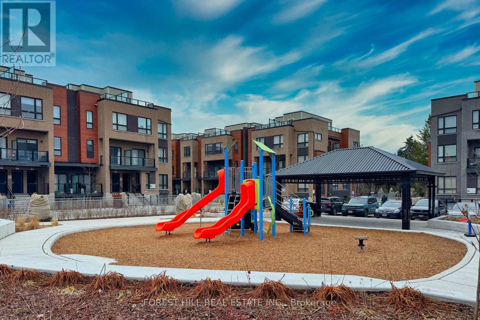 A playground with a red slide in front of apartment buildings.