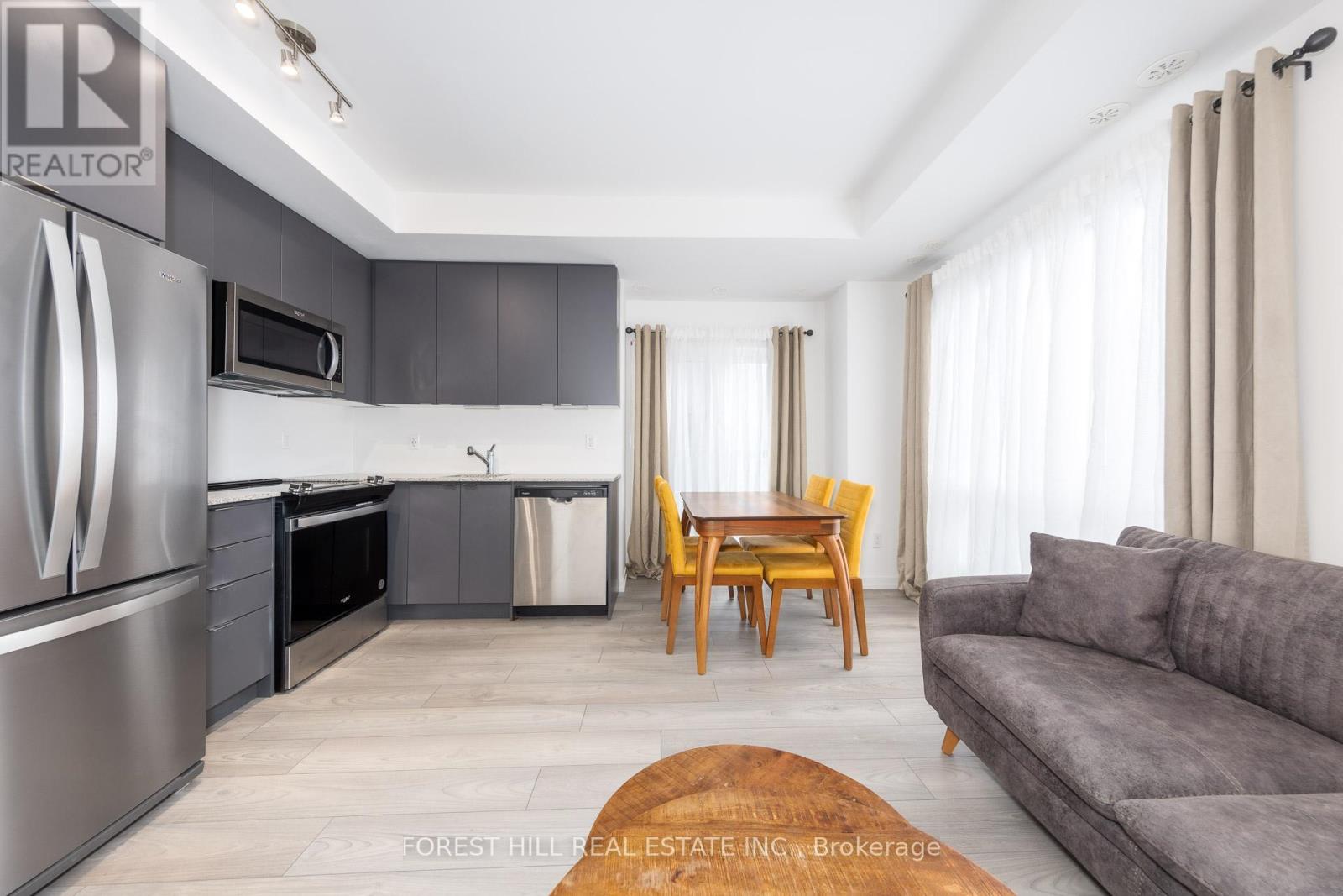 A modern kitchen with a refrigerator, microwave, and a dining table with chairs.