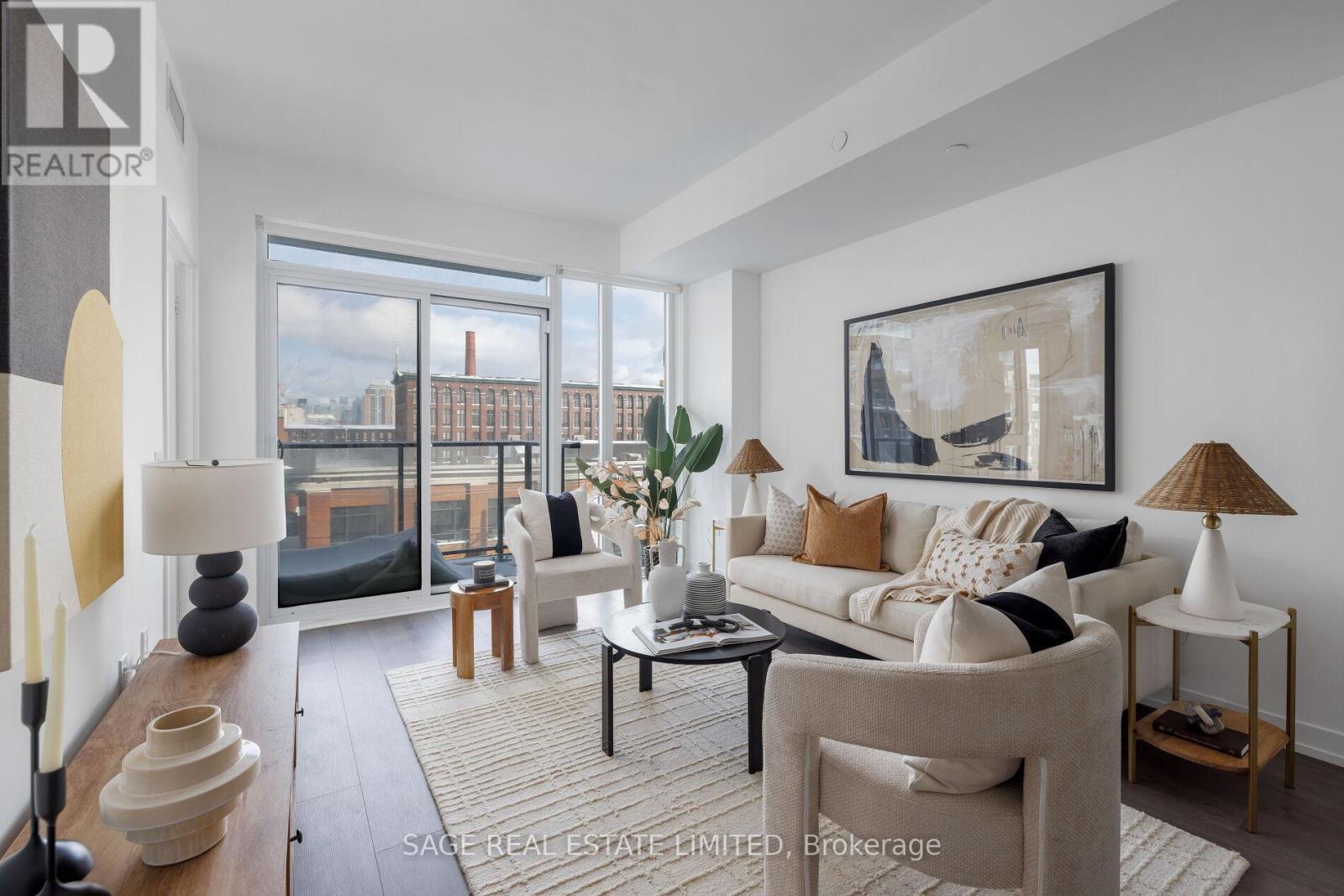 A living room with a large window, a sofa, a coffee table, and a lamp.
