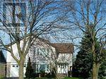 A house with a white facade is surrounded by bare trees.