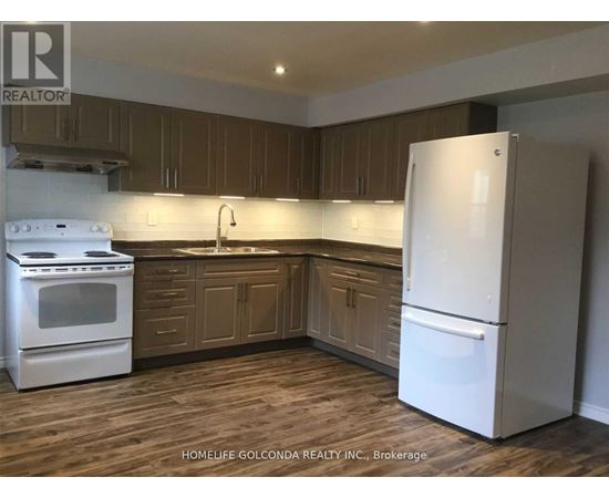 A white refrigerator stands in a kitchen with wooden cabinets and a white stove.