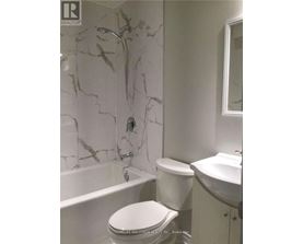 A white toilet sits in a bathroom with marble walls.