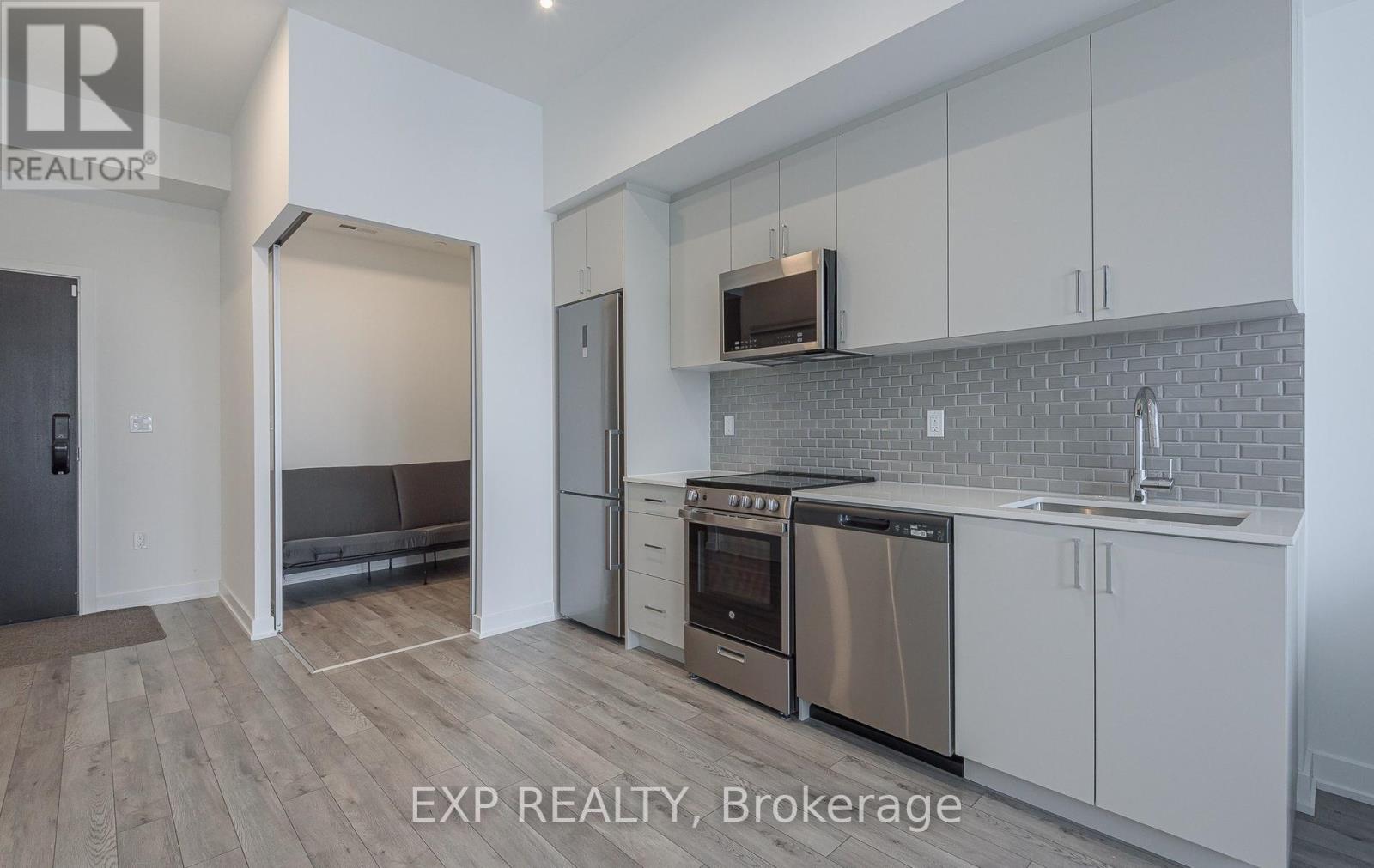 A kitchen with white cabinets and a brick backsplash.