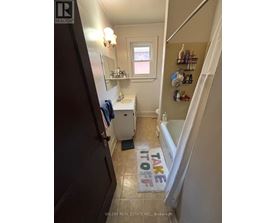 A bathroom with a towel hanging on the door and a window.