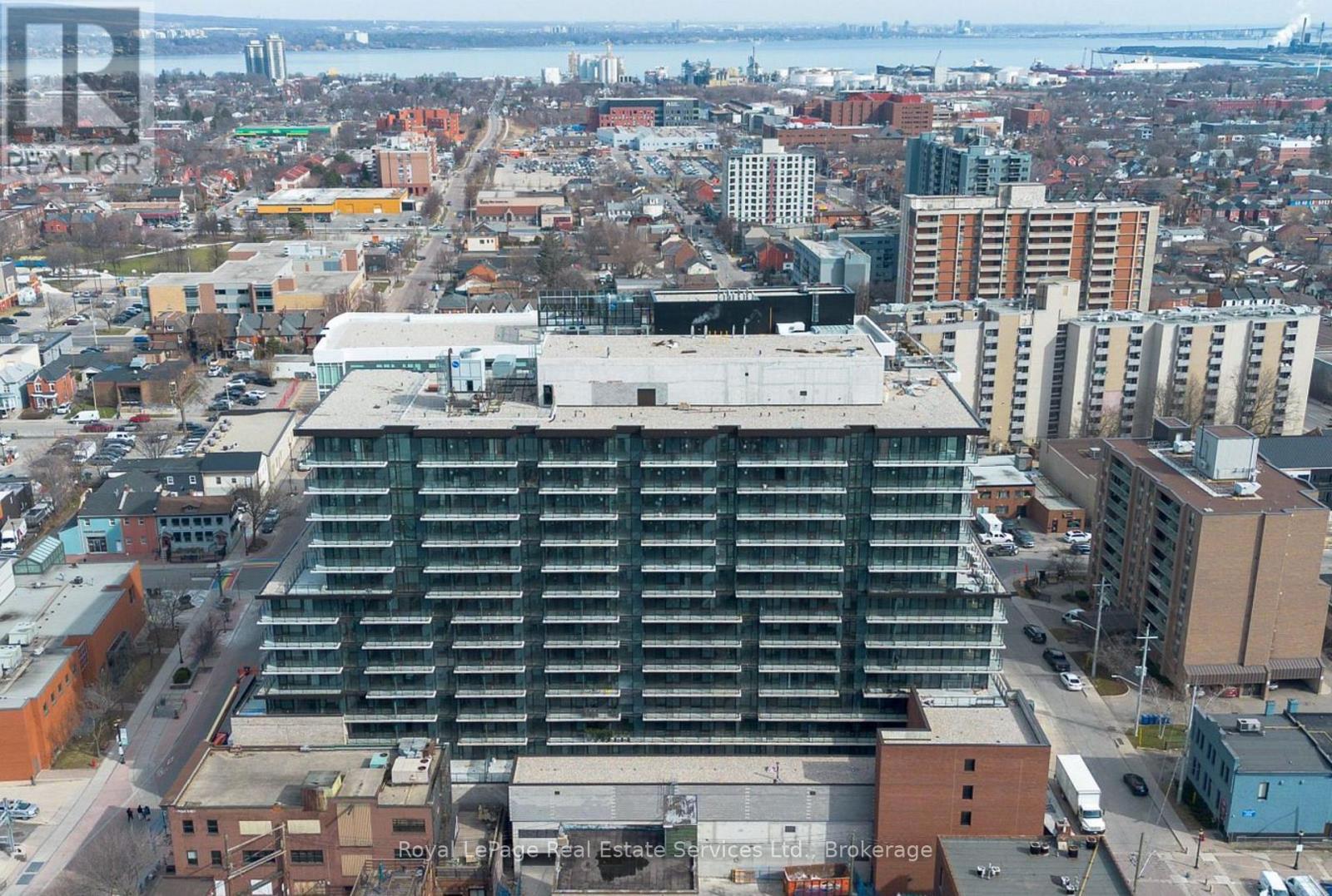 A large building with a flat roof is in the center of a cityscape.